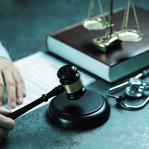 Signos de Medicina Legal, balanza de justicia, martillo, estetoscopio, manos haciendo un informe