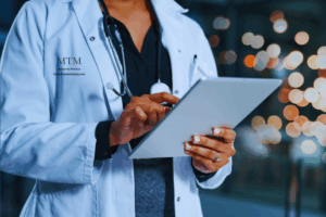 mujer con bata de médico, estetoscopio al cuello, tomando nota
