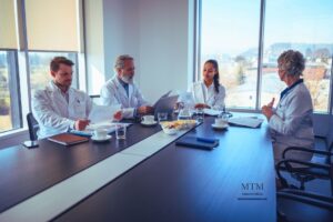 Médicos sentados alrededor de una mesa de trabajo auditando expedientes